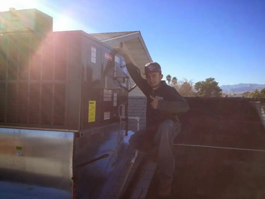HVAC technician performing AC Tune-Up on a rooftop unit in Mendota